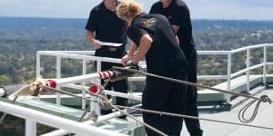 Three Anchor Safe Rope Access technicians prepare for abseil operations from the rooftop of a Sydney high rise building