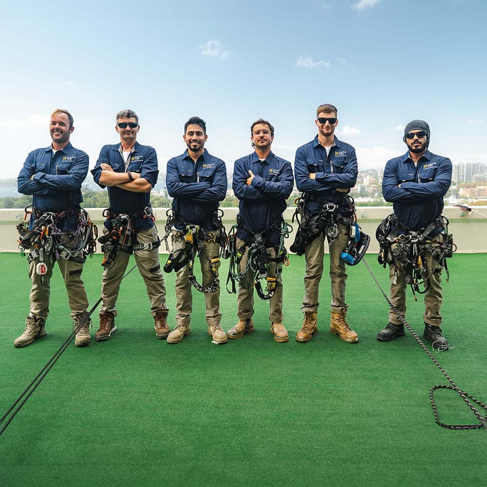 Six Anchor Safe Rope Access team members captured in a group photo on a high-rise roof top